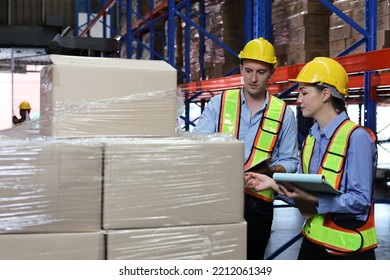 Group Of Warehouse Workers With Hardhats And Reflective Jackets Using Tablet, Walkie Talkie Radio And Cardboard While Controlling Stock And Inventory In Retail Warehouse Logistics, Distribution Center