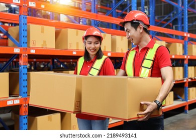 Group Of Warehouse Workers Man And Woman With Hardhats And Reflective Jackets Carrying A Large Box For Delivery To Production Stock And Inventory In Retail Warehouse Logistics, Distribution Center