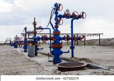 Group of wellheads and pipeline. Oilfield with sand ground. Oil and gas concept. 
