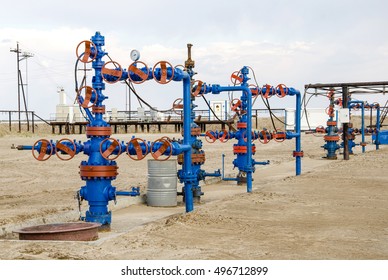 Group of wellheads and pipeline. Oilfield with sand ground. Oil and gas concept. 
