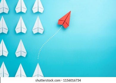 Group Of White Paper Plane In One Direction And One Red Paper Plane Pointing In Different Way On Blue Background. Business For Innovative Solution Concept.