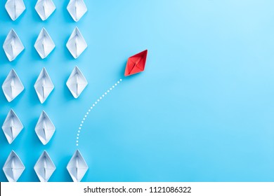 Group of white paper ship in one direction and one red paper ship pointing in different way on blue background. Business for innovative solution concept. - Shutterstock ID 1121086322