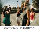 Group of women celebrating on a tennis court, waving and high-fiving each other after a successful team match. Happy and supportive sports environment.