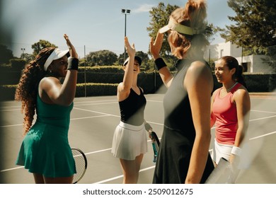 Group of women celebrating on a tennis court, waving and high-fiving each other after a successful team match. Happy and supportive sports environment. - Powered by Shutterstock