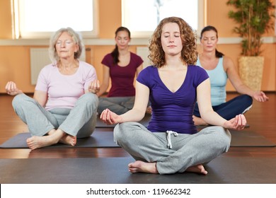 Group of women doing relaxing yoga exercises in gym - Powered by Shutterstock