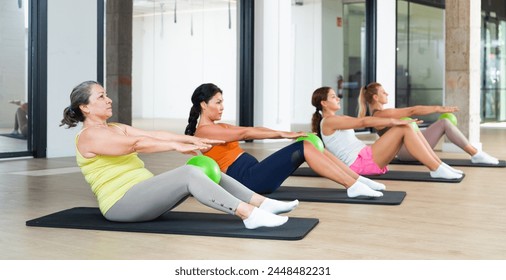 Group of women doing roll up exercise with small pilates ball - Powered by Shutterstock