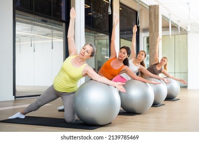 Group of women doing stretching exercises with fitness ball during pilates training - Powered by Shutterstock