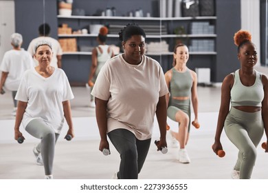 Group of women exercising with dumbbells together during sport training in gym - Powered by Shutterstock