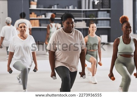 Group of women exercising with dumbbells together during sport training in gym