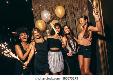 Group of women with fireworks at party. Stylish girls enjoying party at nightclub.