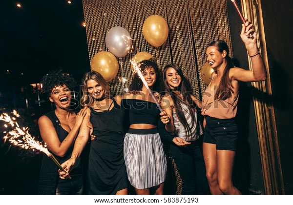 Group of women with fireworks at party.\
Stylish girls enjoying party at\
nightclub.