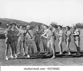 Group of women holding baseball bats and standing in a row - Powered by Shutterstock