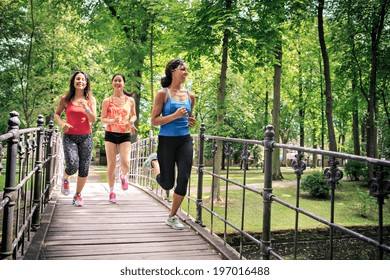 Group Of  Women Jogging By A River In The Old City Park