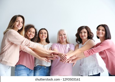 Group of women with silk ribbons joining hands against white background. Breast cancer awareness concept - Shutterstock ID 1293503161