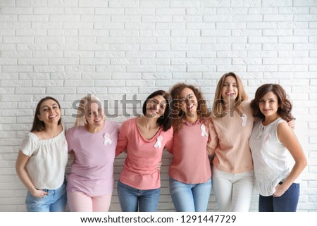 Group of women with silk ribbons near brick wall. Breast cancer awareness concept
