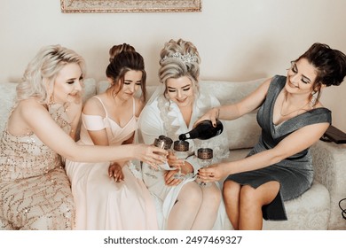 A group of women are sitting on a couch, one of them pouring wine into glasses. Scene is celebratory and happy, as the women are enjoying each other's company and sharing a special moment together - Powered by Shutterstock