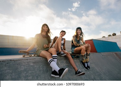 Group of women sitting on ramp in skate park. Female friends enjoying a day at skate park. - Powered by Shutterstock