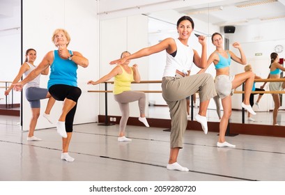Group of women in sportswear performing contemporary dance in training room.