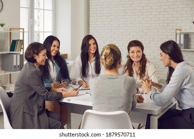 Group Of Women In Their 20s And 30s Meeting Around Office Table. Team Of Businesswomen Or Company Employees Talking, Planning New Project, Discussing Business Strategy, Sharing Opinions And Ideas