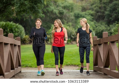Group of women in their 30s walking together in the outdoors. Cute blond and fit women in their mid 30s who are active and working to stay healthy. Full length photo with copy space