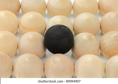 Group Of Wooden Bolls Same In Size, Colour, Texture Representing The Crowd, A Ball Coloured In Black Higher Than Others And On Focus Representing Difference, Or Expression ?Black Sheep?