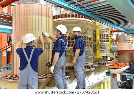 group worker assembles a transformer in mechanical engineering - teamwork at work  