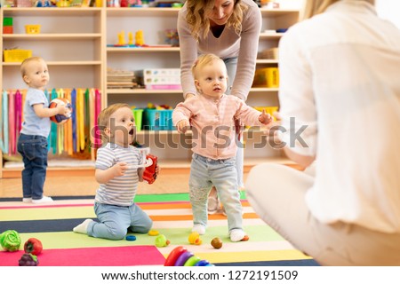 Group of workers with babies in nursery or kindergarten