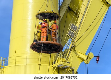 A Group Of Workers Consist Of Riggers And Engineers Riding A Personal Transfer Basket, Transferring From A Tug Boat To Heavy Lift Pipelay Barge At Offshore