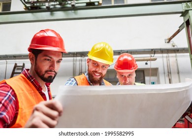 Group Of Workers And Craftsmen With Blueprint Or Floor Plan In A Team Meeting