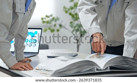 A group of workers discussing something while looking at a catalogue