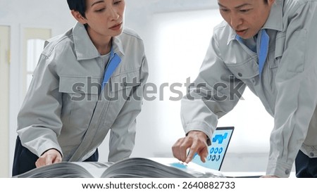 A group of workers discussing something while looking at a catalogue