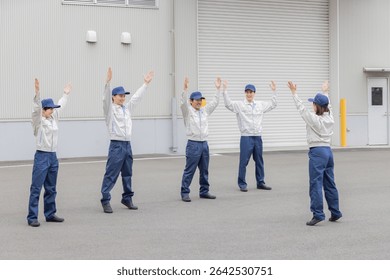 A group of workers doing exercises in front of a factory
