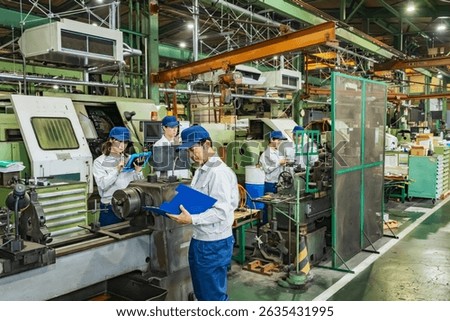 A group of workers operating machine tools in a factory