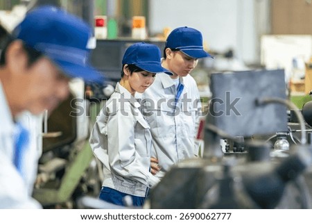 A group of workers operating machine tools in a factory