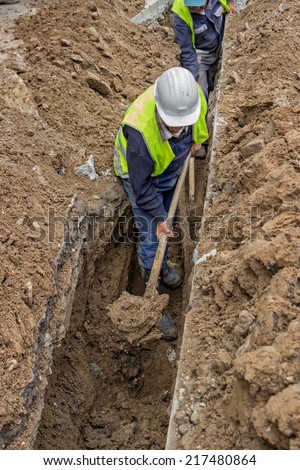 Group of workers with shovels in a trench, dig trenches along the road. Selective focus.