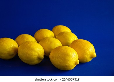 A Group Of Yellow Lemons (Citrus Limon) Against A Deep Blue Background. 