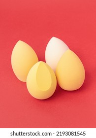 Group Of Yellow Makeup Soft Sponges On Red Background. Makeup Puff