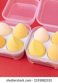 Group Of Yellow Makeup Soft Sponges On Red Background. Makeup Puff In Plastic Case