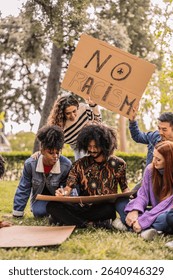 Group of young activists preparing protest signs and placards in a park, getting ready for a demonstration against racism and discrimination