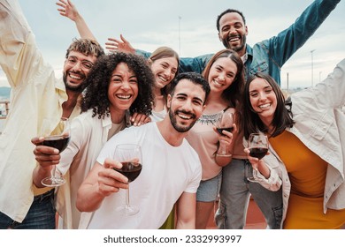 Group of young adult best friends having fun toasting a red wine glasses at rooftop reunion or birthday party, drinking alcohol. Happy people enjoying on a social gathering celebrating together. High - Shutterstock ID 2332993997
