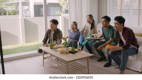 Group Of Young Adult Friend Man And Woman Asia People Sit At Sofa Couch Joy Chanting Party Fun Game FIFA World Cup Live TV At Home Eat Snack Bowl Drink Beer Bottle Glass Jump Mad Happy Win Exult Face.