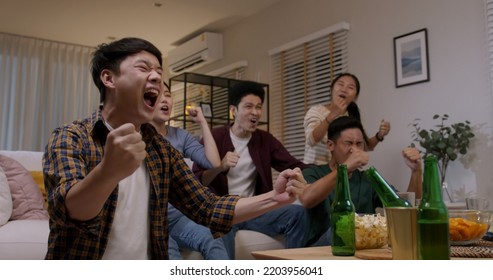 Group of young adult friend man and woman asia people sit at sofa couch joy night party fun game FIFA world cup live TV at home eat snack bowl drink beer bottle glass jump mad happy win exult face. - Shutterstock ID 2203956041