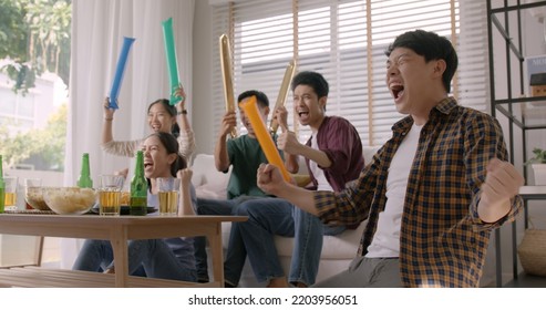 Group of young adult friend man and woman asia people sit at sofa couch joy chanting party fun game FIFA world cup live TV at home eat snack bowl drink beer bottle glass jump mad happy win exult face. - Powered by Shutterstock