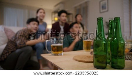 Group of young adult friend man and woman asia people sit at sofa couch joy night party fun game FIFA world cup live TV at home eat snack bowl drink beer bottle glass jump mad happy win exult face.