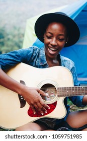 Group Of Young Adult Friends In Camp Site Playing Guitar And Singing Together Outdoors Recreational Leisure And Friendship Concept