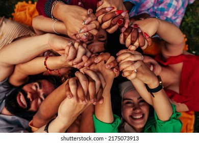 A Group Of Young Adult Multi Racial People Are Lying In Circle On The Grass And Holding Their Hands Up Above Their Heads