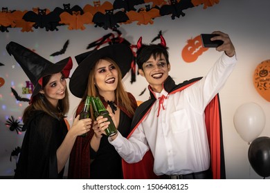 Group of young adult and teenager people celebrating a Halloween party carnival Festival in Halloween costumes drinking alcohol beer and take selfie photographing.