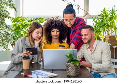 Group Of Young Adults Discussing A Serious Start Up Project In Coworking Space Indoor. Diverse Students Working Together On Laptop And Tablet In Office. Teamwork, Brainstorming And Technology Concept