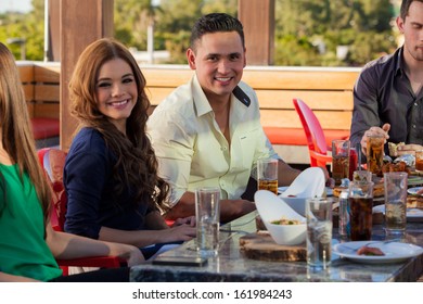 Group Of Young Adults Eating Out And Drinking At A Restaurant Outdoors