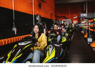 Group of young adults riding go-karts in an indoor racing track, smiling and having fun. - Powered by Shutterstock